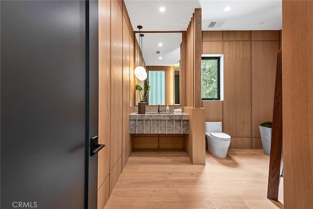 bathroom with toilet, wood finished floors, vanity, and recessed lighting