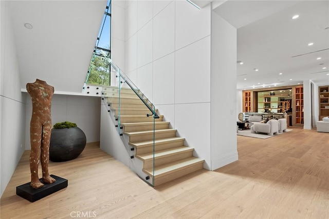 stairs with wood finished floors and recessed lighting