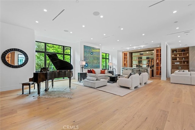 living area with light wood-style floors, recessed lighting, baseboards, and built in shelves