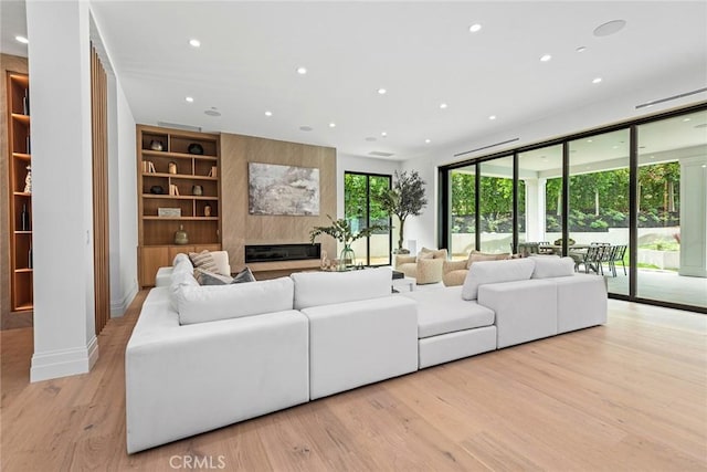 living area featuring recessed lighting, a fireplace, light wood-style floors, built in shelves, and baseboards