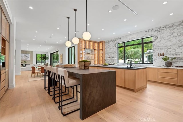 kitchen featuring a large island, light brown cabinets, dark countertops, light wood-type flooring, and recessed lighting