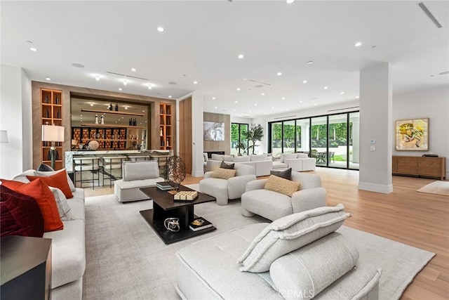 living room featuring recessed lighting, bar area, light wood-type flooring, and baseboards