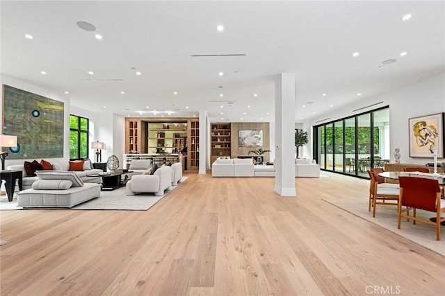 living area with recessed lighting, light wood finished floors, plenty of natural light, and built in features