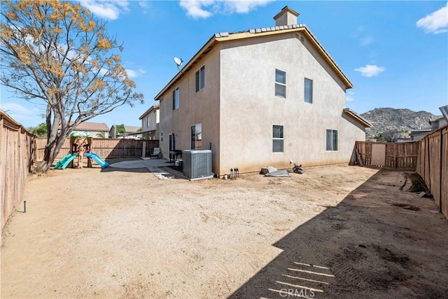 3260 Ivy Ct, Perris, CA 92571 - rear view of property featuring central AC unit, a fenced backyard, stucco siding, and a playground