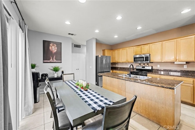 3260 Ivy Ct, Perris, CA 92571 - kitchen with appliances with stainless steel finishes, light brown cabinets, a kitchen island with sink, dark stone counters, and recessed lighting