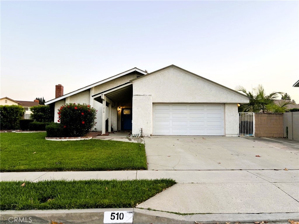 510 Carnation Dr, Placentia, CA 92870 - view of front of home featuring a garage, stucco siding, driveway, a gate, and a chimney