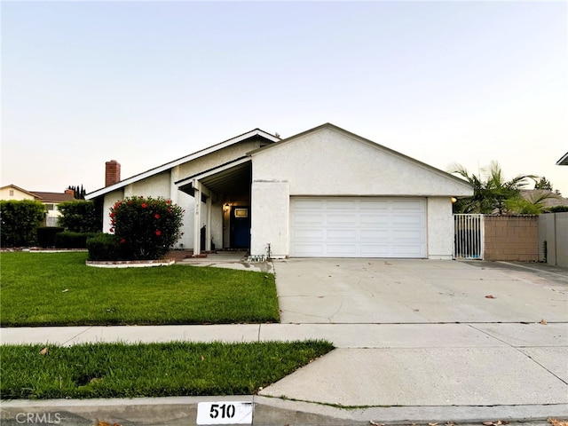 510 Carnation Dr, Placentia, CA 92870 - view of front of home featuring a garage, stucco siding, driveway, a gate, and a chimney