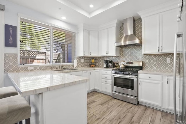 11372 Via Rancho San Diego Unit B, El Cajon, CA 92019 - kitchen with wall chimney exhaust hood, gas range, a sink, a peninsula, and light wood-style flooring