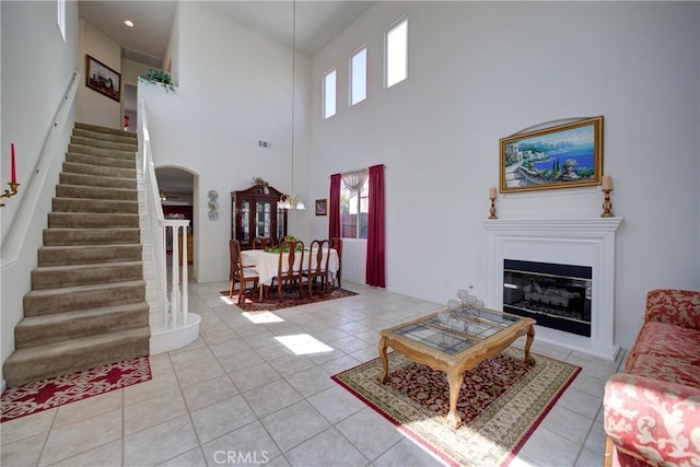 932 Provance Ave, Santa Maria, CA 93458 - living room featuring stairway, arched walkways, a towering ceiling, light tile patterned floors, and a glass covered fireplace