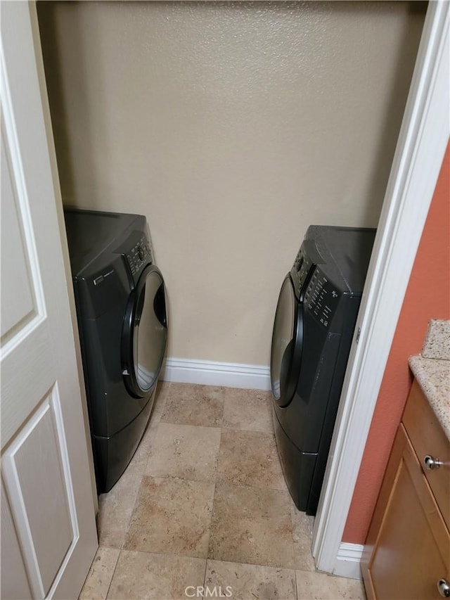 22681 Oakgrove Unit 536, Aliso Viejo, CA 92656 - laundry room featuring washer / clothes dryer, stone tile flooring, baseboards, and cabinet space