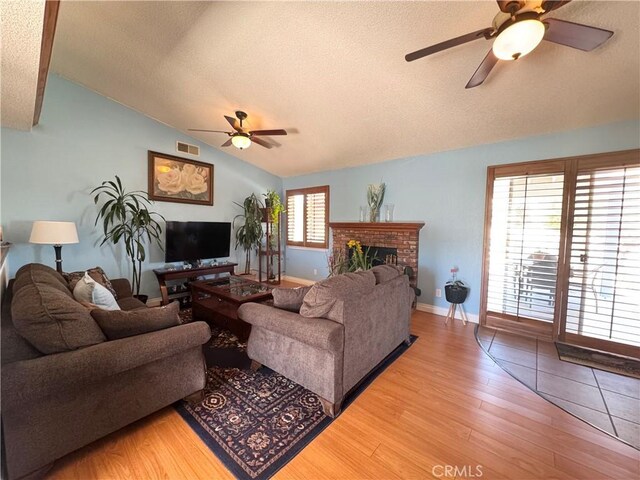 7446 Bangor Ave, Hesperia, CA 92345 - living room featuring ceiling fan, lofted ceiling, a textured ceiling, light wood-style floors, and a brick fireplace