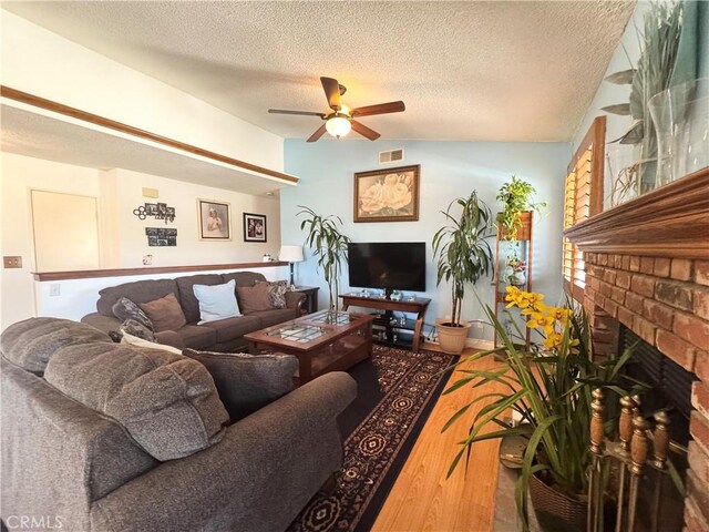 7446 Bangor Ave, Hesperia, CA 92345 - living room with a ceiling fan, a fireplace, a textured ceiling, and wood finished floors