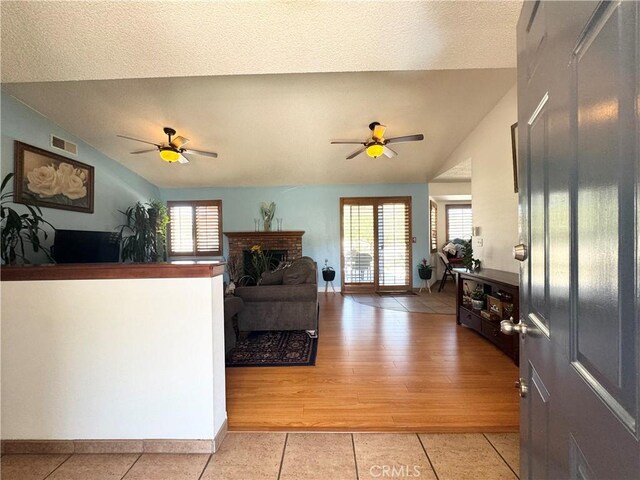 7446 Bangor Ave, Hesperia, CA 92345 - living room with vaulted ceiling, ceiling fan, plenty of natural light, light tile patterned floors, and a fireplace