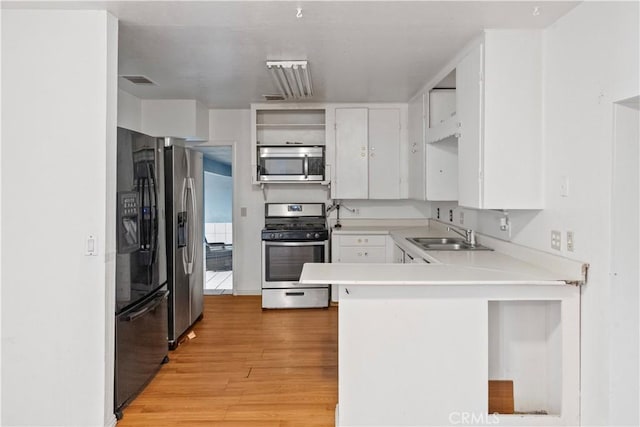 5219 Fleming Rd, Atwater, CA 95301 - kitchen featuring appliances with stainless steel finishes, a sink, a peninsula, light wood-style floors, and white cabinetry