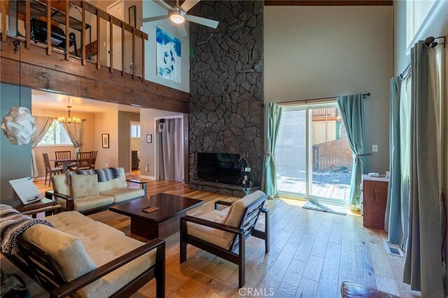 31045 Valley Oak Dr, Running Springs, CA 92382 - living area featuring a high ceiling, hardwood / wood-style floors, a chandelier, ceiling fan, and a stone fireplace