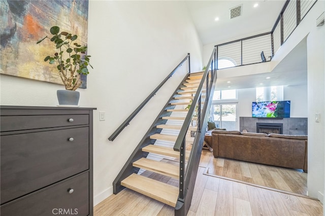 528 San Andres Dr, Solana Beach, CA 92075 - staircase featuring a fireplace, a towering ceiling, and wood finished floors