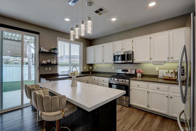 29567 Castlewood Dr, Menifee, CA 92584 - kitchen featuring appliances with stainless steel finishes, white cabinetry, decorative light fixtures, dark wood finished floors, and recessed lighting