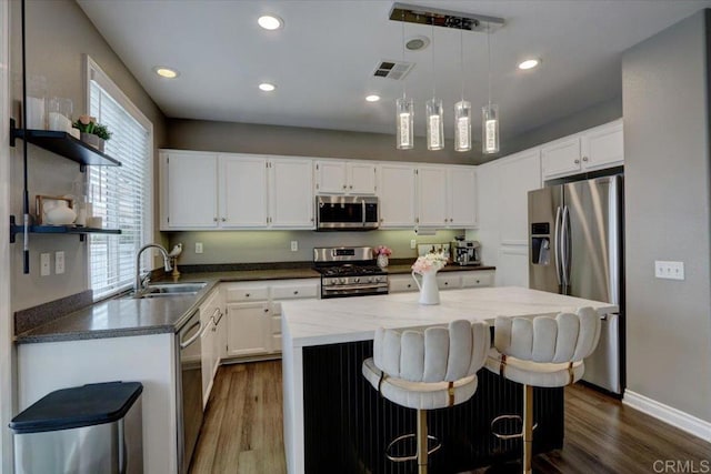 29567 Castlewood Dr, Menifee, CA 92584 - kitchen featuring stainless steel appliances, a sink, dark wood-style flooring, white cabinetry, and a kitchen island