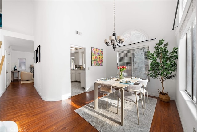 10274 Corkwood Ct, Rancho Cucamonga, CA 91737 - dining space with a chandelier, a towering ceiling, wood finished floors, and baseboards