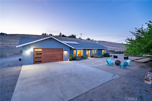 2750 Lazy Hill Rd, San Miguel, CA 93451 - view of front facade featuring solar panels, an attached garage, an outdoor fire pit, driveway, and stucco siding