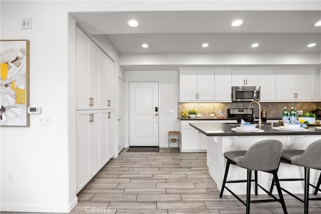 405 Mallorca Ln, Brea, CA 92823 - kitchen with stainless steel appliances, a breakfast bar area, light wood-style floors, backsplash, and recessed lighting