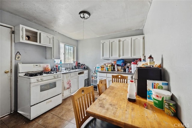 673 W 9th St, San Bernardino, CA 92410 - kitchen with white gas range oven, white cabinets, tile patterned floors, light countertops, and a textured ceiling