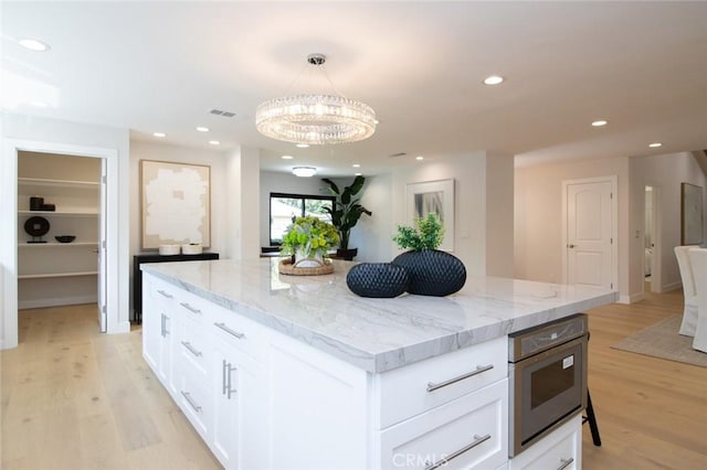 12312 Eveningside Dr, Santa Ana, CA 92705 - kitchen with light wood-type flooring, white cabinetry, light stone counters, recessed lighting, and decorative light fixtures