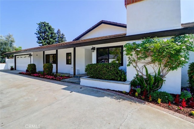 12312 Eveningside Dr, Santa Ana, CA 92705 - view of front of house with stucco siding, an attached garage, a porch, and concrete driveway