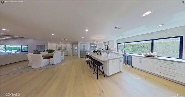 12312 Eveningside Dr, Santa Ana, CA 92705 - kitchen featuring white cabinetry, light wood-type flooring, beverage cooler, recessed lighting, and a kitchen breakfast bar
