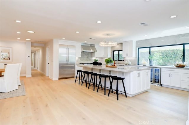 12312 Eveningside Dr, Santa Ana, CA 92705 - kitchen with stainless steel built in fridge, wine cooler, wall chimney exhaust hood, recessed lighting, and white cabinets