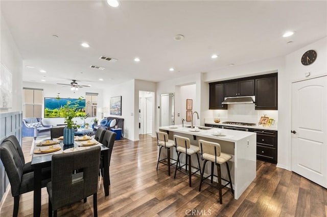 2974 E Walking Beam Pl, Brea, CA 92821 - kitchen with under cabinet range hood, stainless steel gas stovetop, open floor plan, a center island with sink, and a sink