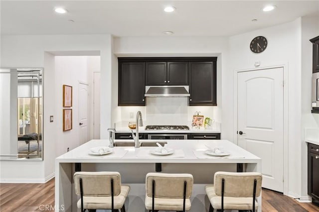 2974 E Walking Beam Pl, Brea, CA 92821 - kitchen featuring dark wood-style floors, light countertops, a breakfast bar area, under cabinet range hood, and a sink