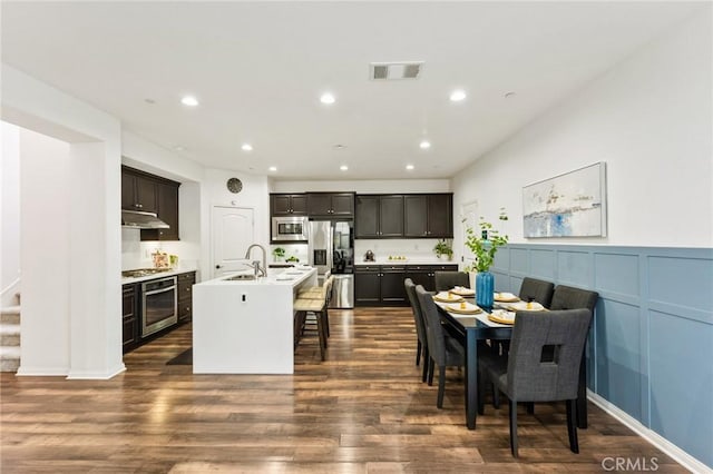 2974 E Walking Beam Pl, Brea, CA 92821 - kitchen featuring appliances with stainless steel finishes, under cabinet range hood, dark wood-type flooring, a kitchen bar, and recessed lighting