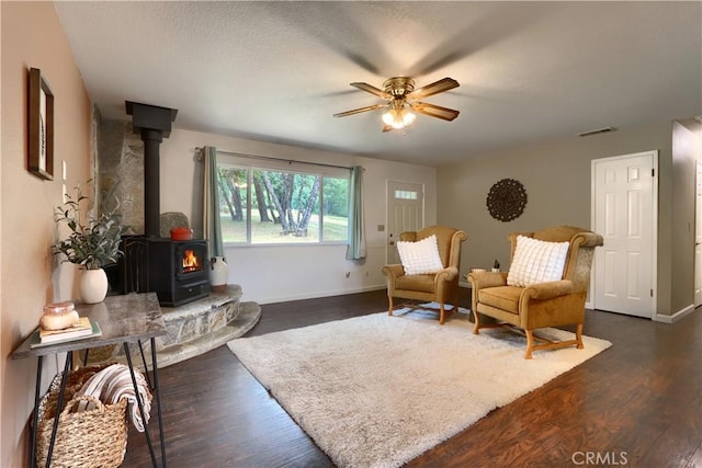 51864 Mountain Quail Pl, Oakhurst, CA 93644 - living room featuring a wood stove, ceiling fan, dark wood-type flooring, and baseboards