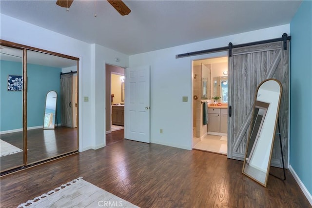 51864 Mountain Quail Pl, Oakhurst, CA 93644 - unfurnished bedroom with a barn door, dark wood-type flooring, baseboards, and a closet