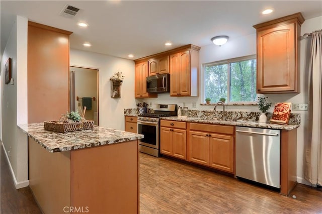 51864 Mountain Quail Pl, Oakhurst, CA 93644 - kitchen with appliances with stainless steel finishes, light stone countertops, a peninsula, wood finished floors, and recessed lighting