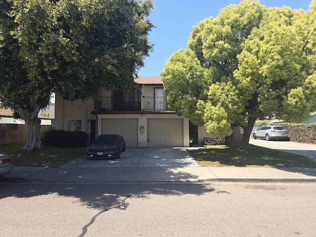 117076 11th St, Imperial Beach, CA 91932 - view of property hidden behind natural elements with concrete driveway, a balcony, stucco siding, and an attached garage