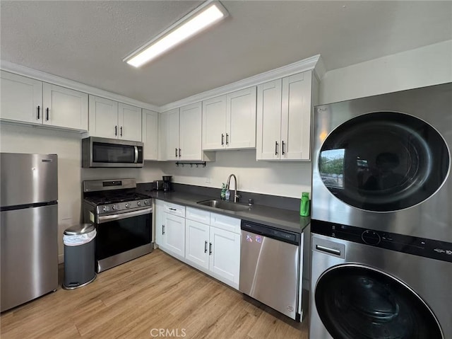 951 E Elma St, Ontario, CA 91764 - kitchen featuring appliances with stainless steel finishes, stacked washer / dryer, a sink, dark countertops, and light wood-style flooring