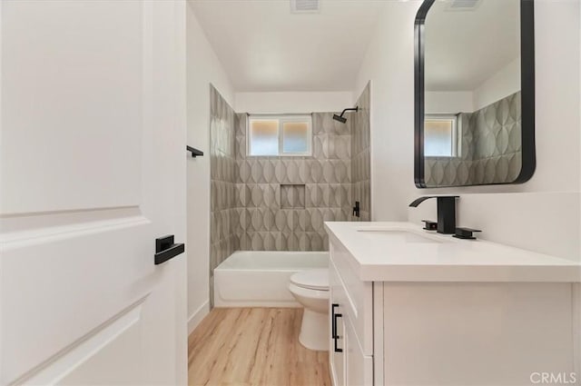 full bath with toilet, wood finished floors, vanity, and  shower combination