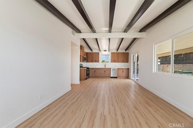 unfurnished living room featuring baseboards, beamed ceiling, light wood-style floors, and a sink