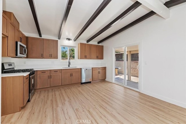 kitchen featuring stainless steel appliances, a sink, light wood-type flooring, light countertops, and baseboards
