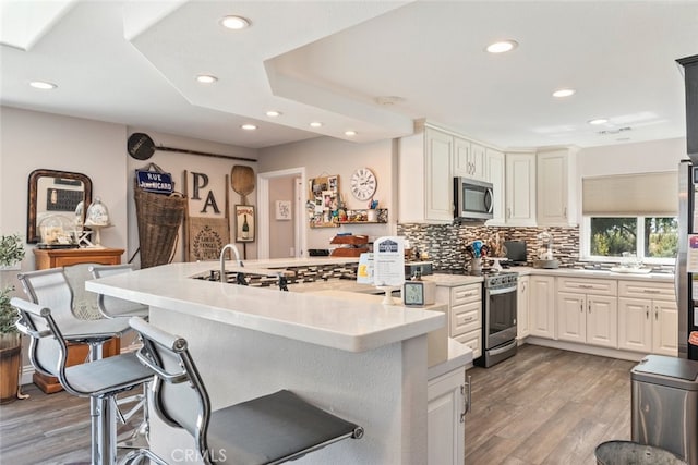 38855 Bella Vista Rd, Temecula, CA 92592 - kitchen with stainless steel appliances, a kitchen breakfast bar, recessed lighting, light wood-style flooring, and backsplash