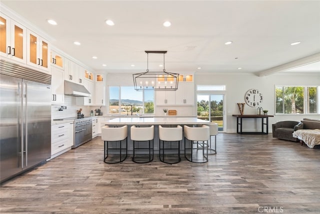 38855 Bella Vista Rd, Temecula, CA 92592 - kitchen featuring stainless steel built in refrigerator, under cabinet range hood, a kitchen breakfast bar, white cabinetry, and light countertops