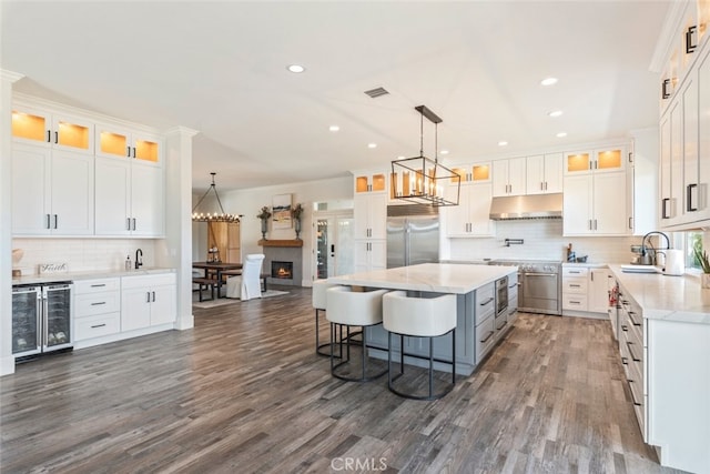 38855 Bella Vista Rd, Temecula, CA 92592 - kitchen with appliances with stainless steel finishes, wine cooler, under cabinet range hood, a sink, and decorative backsplash