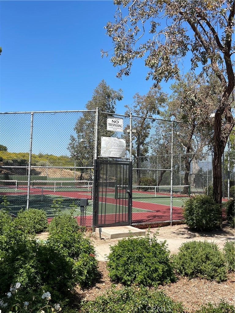 view of tennis court with a gate