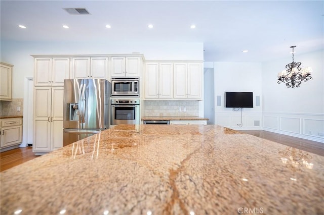 18337 Chatham Ln, Porter Ranch, CA 91326 - kitchen with appliances with stainless steel finishes, light stone countertops, backsplash, wood finished floors, and a chandelier