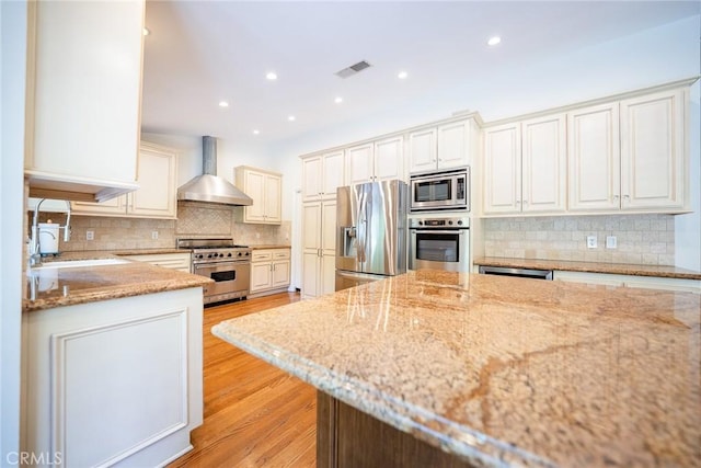 18337 Chatham Ln, Porter Ranch, CA 91326 - kitchen with appliances with stainless steel finishes, wall chimney range hood, light stone counters, decorative backsplash, and recessed lighting