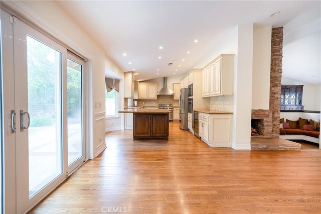 18337 Chatham Ln, Porter Ranch, CA 91326 - kitchen featuring wall chimney range hood, open floor plan, stainless steel appliances, a center island, and light wood-type flooring