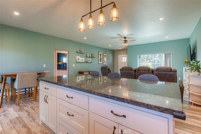 5981 Kibler Rd, Paradise, CA 95969 - kitchen featuring light wood-style floors, white cabinetry, dark stone countertops, a ceiling fan, and a kitchen island