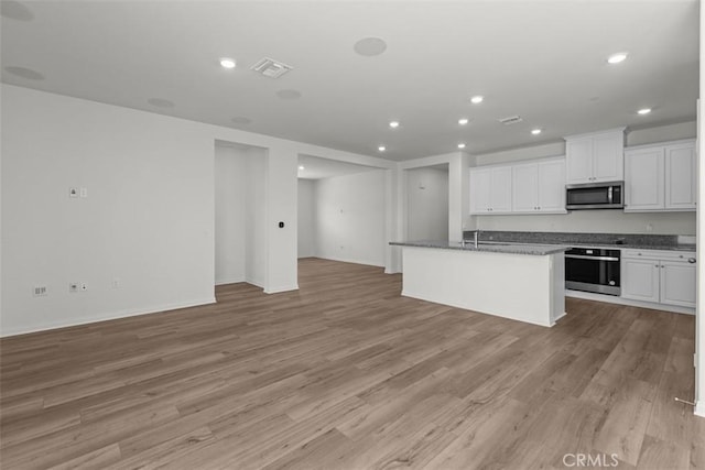 30773 Vera Cruz Cir, Winchester, CA 92596 - kitchen with appliances with stainless steel finishes, open floor plan, light wood finished floors, white cabinets, and a center island with sink